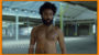 A shirtless black man with curly hair and a beard walks in an empty parking garage; the text "hollywood.tv" is visible in the foreground.