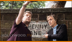 Two men point and look at historic graffiti on a wall, one gesturing upward, with a hollywood.tv watermark at the bottom.