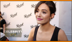 Woman at celebrity event, smiling for the camera with branded backdrop.