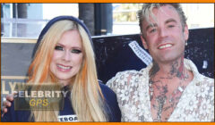 Avril lavigne and mod sun smiling together at a celebrity event, both dressed casually with visible tattoos.